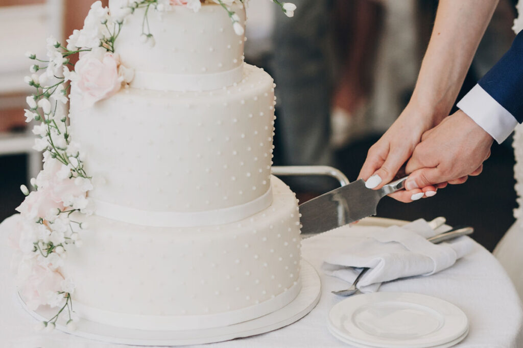 bride and groom's hands holding a knife, cutting their wedding cake together