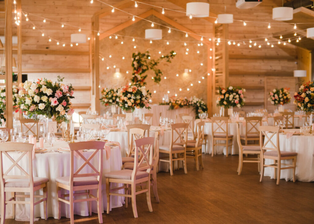 tables decorated inside a wedding venue with flowers and string lights above