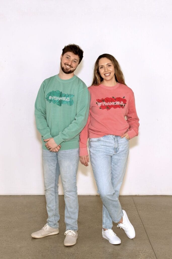 man and woman standing in logo sweatshirts