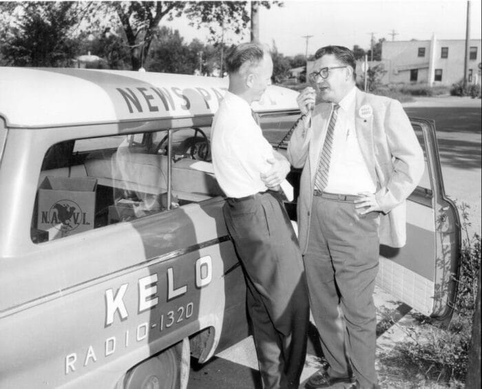 two men talking outside car old photo