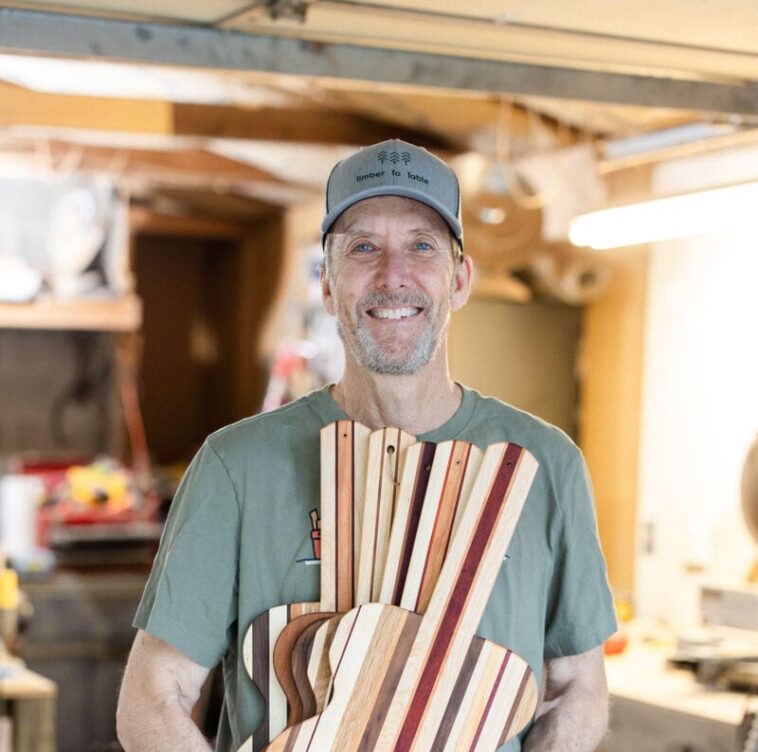man holding wooden guitars e1730319292374