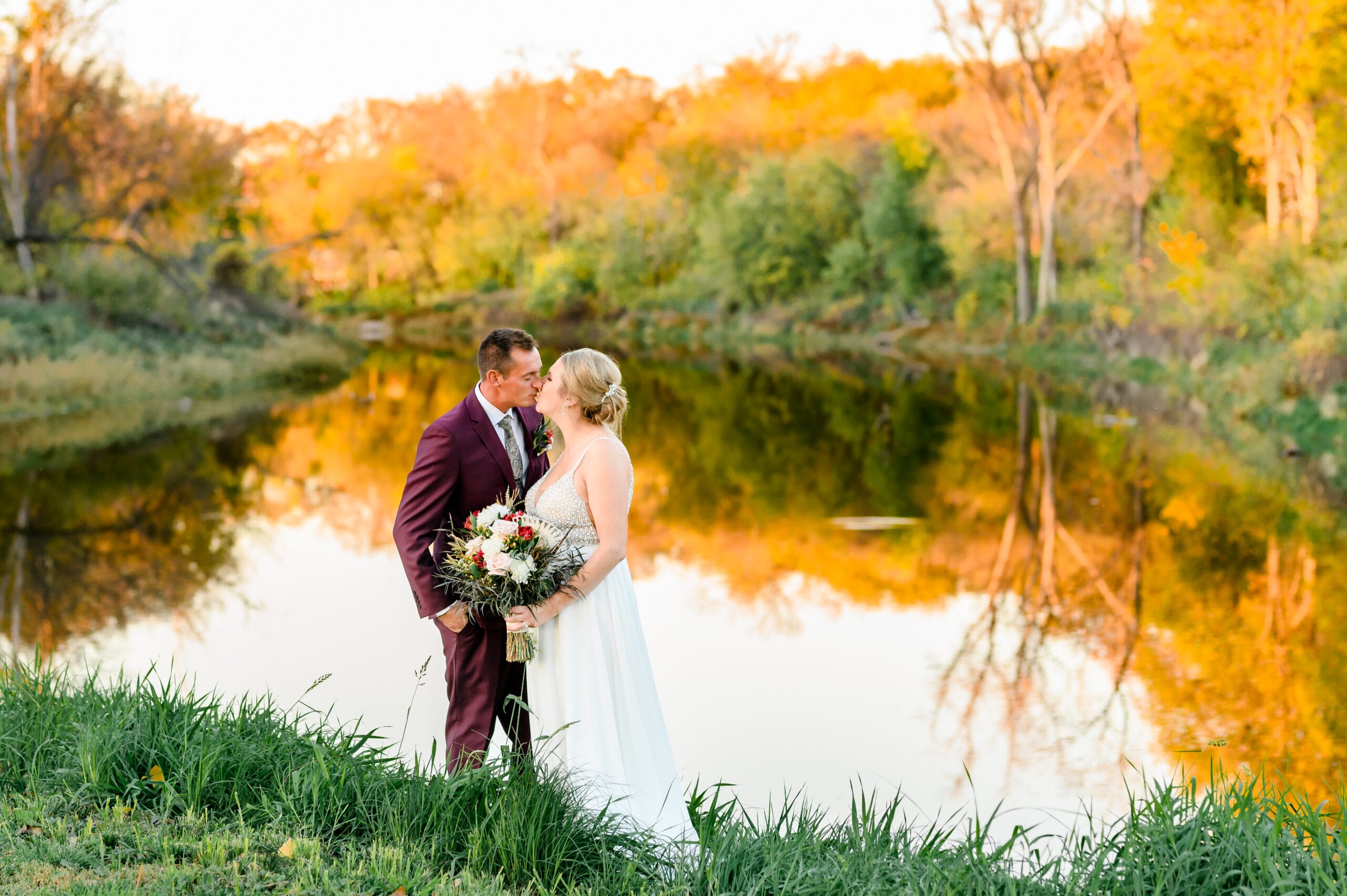 couple posing on wedding day in front of fall scenery scaled