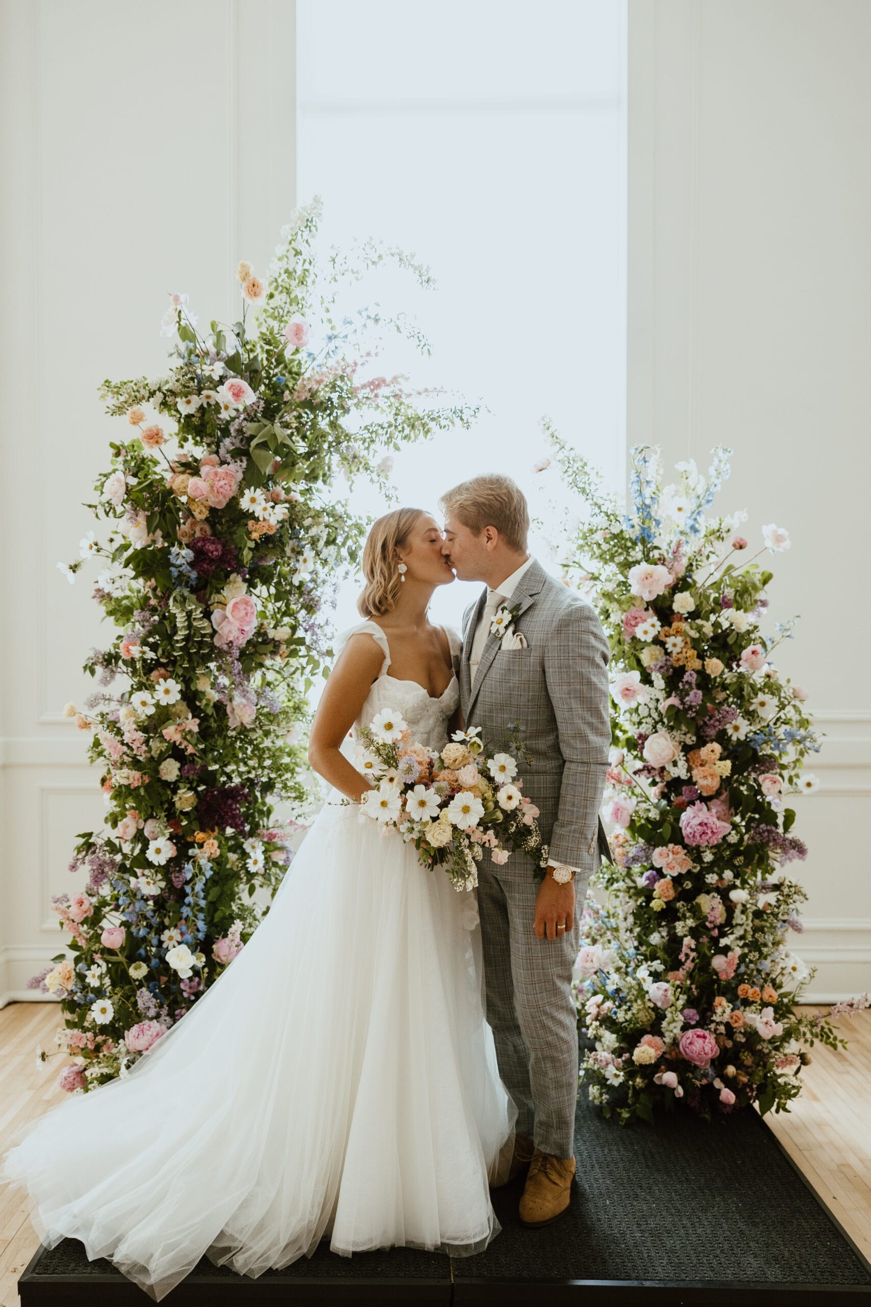 couple standing at flower alter getting married scaled