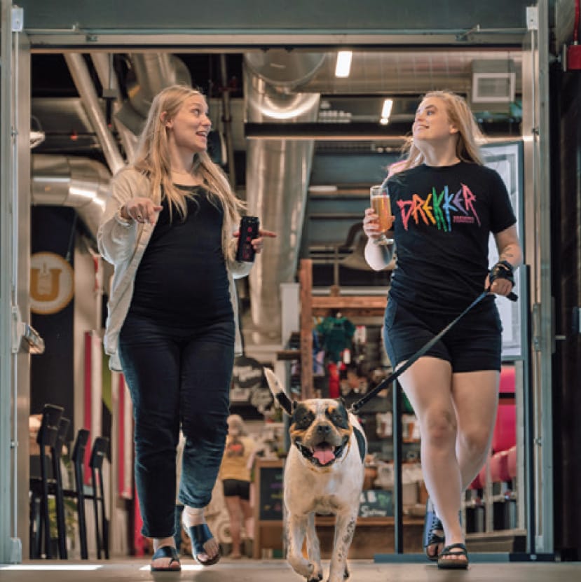 two women walking dog inside